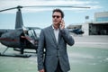 Businessman talking on cellphone near private helicopter