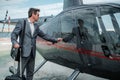 Businessman talking on cellphone near private helicopter