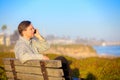 Businessman talking on cellphone outdoors, park bench by ocean Royalty Free Stock Photo