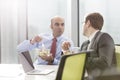 Businessman talking with colleague while eating lunch in boardroom during meeting at office Royalty Free Stock Photo