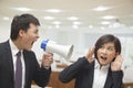 Businessman Talking into Megaphone by Businesswoman's Ear Royalty Free Stock Photo