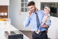 Businessman talking on mobile phone while carrying daughter