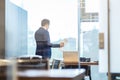 Businessman talking on a mobile phone while looking through window. Royalty Free Stock Photo