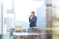 Businessman talking on a mobile phone while looking through office window. Royalty Free Stock Photo