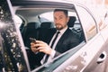 Businessman talking on the mobile phone and looking outside the window while sitting on back seat of car. Male business executive Royalty Free Stock Photo