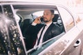 Businessman talking on the mobile phone and looking outside the window while sitting on back seat of car. Male business executive Royalty Free Stock Photo