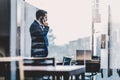 Businessman talking on a mobile phone while looking through window in NY Royalty Free Stock Photo