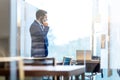 Businessman talking on a mobile phone while looking through window in NY Royalty Free Stock Photo