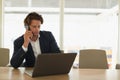 Businessman talking on mobile phone while using laptop in the conference room Royalty Free Stock Photo