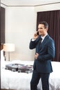 Businessman in formal suit talking on phone in hotel room with open suitcase Royalty Free Stock Photo