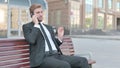 Businessman Talking on Phone while Sitting Outdoor on Bench Royalty Free Stock Photo