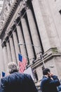 Businessman talking on the phone on Wall street in New York with American flags and New York Stock Exchange in