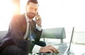 Foreground businessman talking on a smartphone