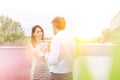 Businessman talking to businesswoman during coffee break in office rooftop with yellow lens flare in background Royalty Free Stock Photo