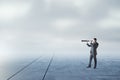 Businessman with telescope looking into the distance on abstract dull sky and ground background