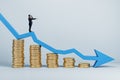 Businessman with telescope standing on abstract falling golden coins chart with blue downward arrow in light interior. Financial