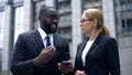 Businessman telling female colleague about useful application in smartphone