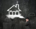 Businessman thinking about house shape cloud with doodles wall Royalty Free Stock Photo