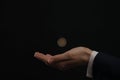 Businessman throwing coin on black background, closeup Royalty Free Stock Photo