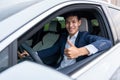 A businessman thumbs up while sitting in a new electric car with a happy smile. EV Car. EV vehicle. Concept of green energy and Royalty Free Stock Photo