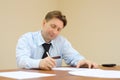 Businessman in tie sits at table and signs documents Royalty Free Stock Photo