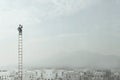 Businessman at the top of a long ladder observes the city with his binoculars