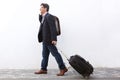 Businessman traveling with his suitcase and talking on cell phone outdoors Royalty Free Stock Photo