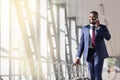 Businessman traveller talking on phone,walking inside airport, carrying suitcase Royalty Free Stock Photo