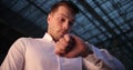 Businessman in a trip. Busy young handsome man looks around and on his armwatch waiting for a taxi outside