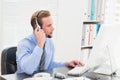 Businessman typing at computer while speaking with headset Royalty Free Stock Photo