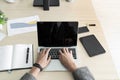 The businessman while typing an information on laptop with office accesssories setting on wood table. /Business and technology con