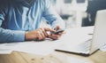 Businessman typing text smartphone. Generic design laptop on the table. Blurred background, horizontal mockup.