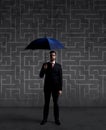 Businessman with umbrella standing over labyrinth background. Business, strategy, insurance, concept. Royalty Free Stock Photo