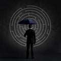 Businessman with umbrella standing over labyrinth background. Business, strategy, insurance, concept.