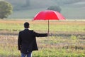 Businessman with umbrella in a field - insurance and protection concept Royalty Free Stock Photo