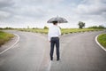 Businessman with umbrella standing at crossroads. Concept of choice