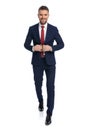 Businessman unbuttoning his jacket, smiling and walking towards the camera Royalty Free Stock Photo