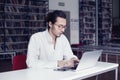 Businessman, university student writing and working at laptop, in a public co-working or library Royalty Free Stock Photo