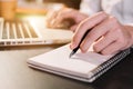 Businessman use a laptop and take notes in the notebook at the office desk.