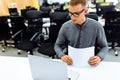 Businessman uses a laptop while sitting at his desk. young man develops business plans with documents on his desk Royalty Free Stock Photo