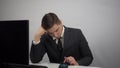 The businessman uses the phone lying on the table with his head down. A young man in a suit is sitting in the office. Royalty Free Stock Photo