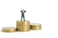 Businessman using binoculars standing above coin money stack. Miniature tiny people toys photography. isolated on white background