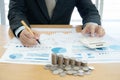 Businessman using calculator and tablet with stacked coins arranged