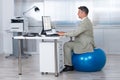 Businessman Using Computer While Sitting On Exercise Ball Royalty Free Stock Photo