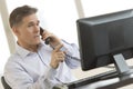 Businessman Using Landline Phone While Pointing At Computer Royalty Free Stock Photo