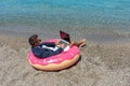 Businessman using laptop computer on inflatable donut on tropical beach. Summer vacation concept Royalty Free Stock Photo