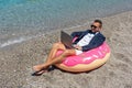 Businessman using laptop computer on inflatable donut on tropical beach. Summer vacation concept Royalty Free Stock Photo