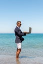 Businessman using laptop computer on tropical beach. Summer vacation concept Royalty Free Stock Photo