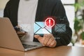 A businessman using a laptop at home is receiving email warning alerts about spam, viruses, and hackers, as well as network