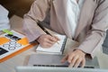 Businessman using laptop to work and writing on notebook with pen in office. Royalty Free Stock Photo